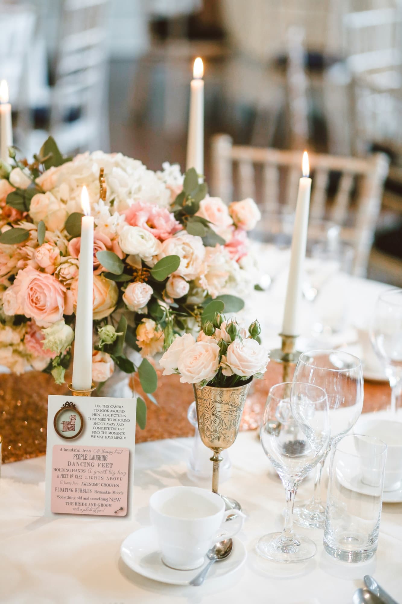 A reception table: candles, roses and glassware set for dinner.